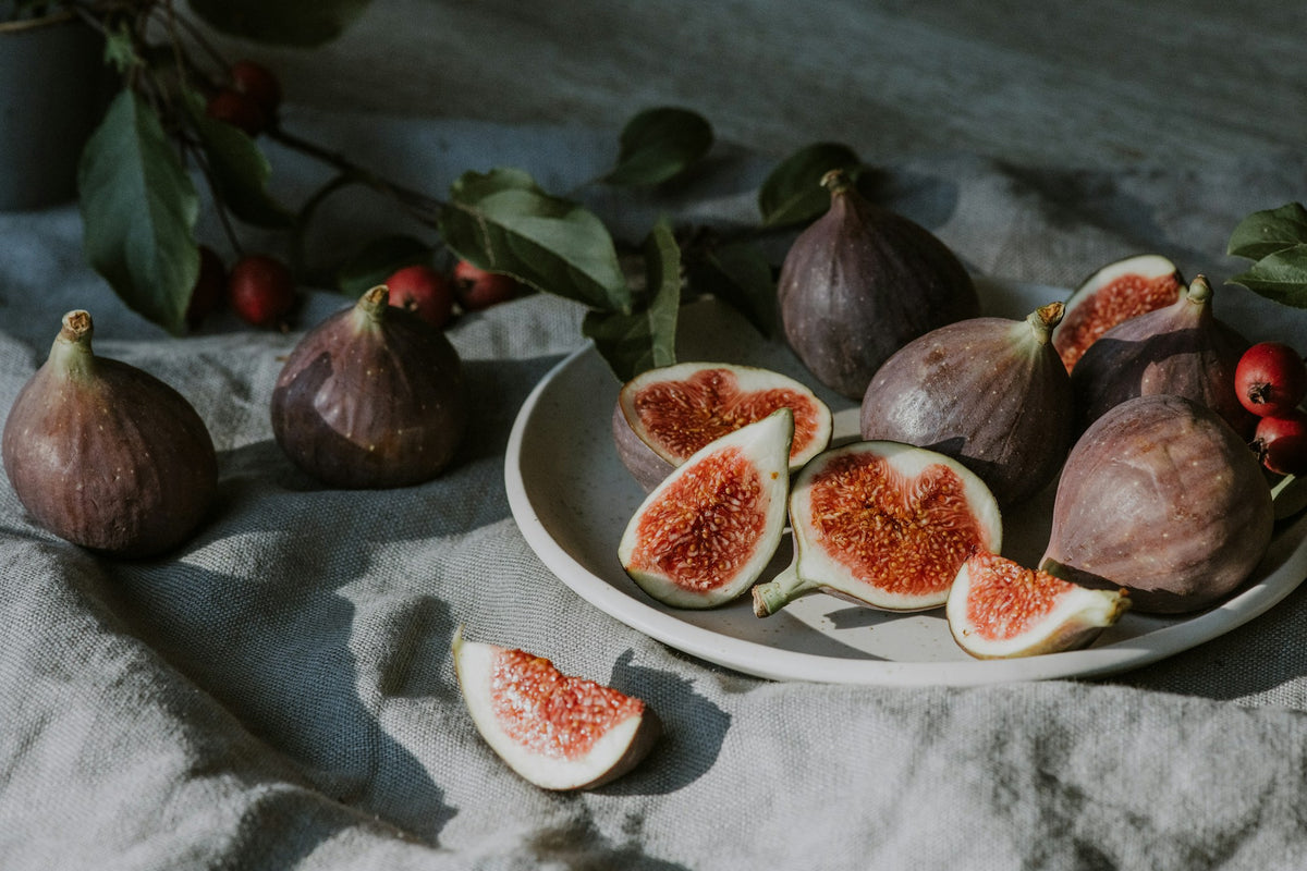 Figues fraîches et feuilles de figuier sur une assiette