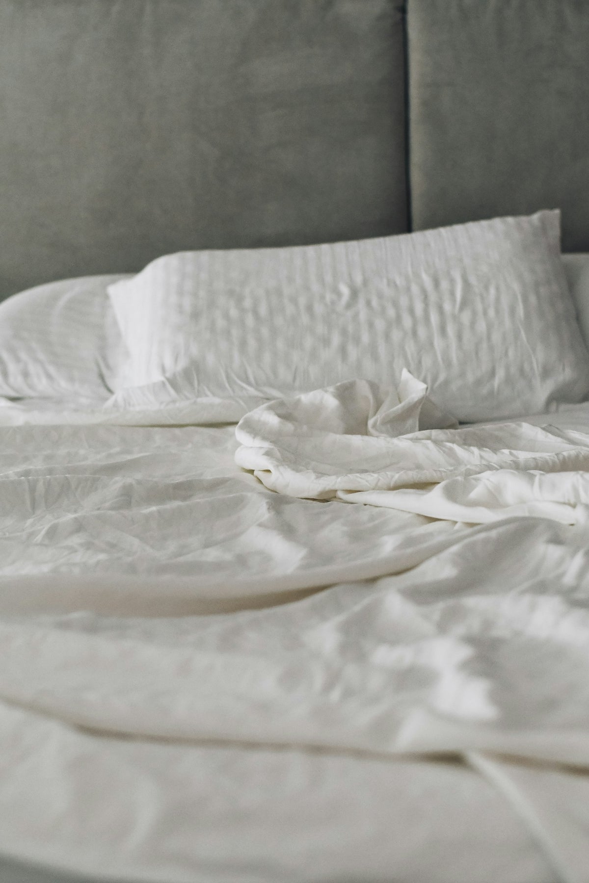 Lit aux draps de lin blanc dans la lumière douce du matin